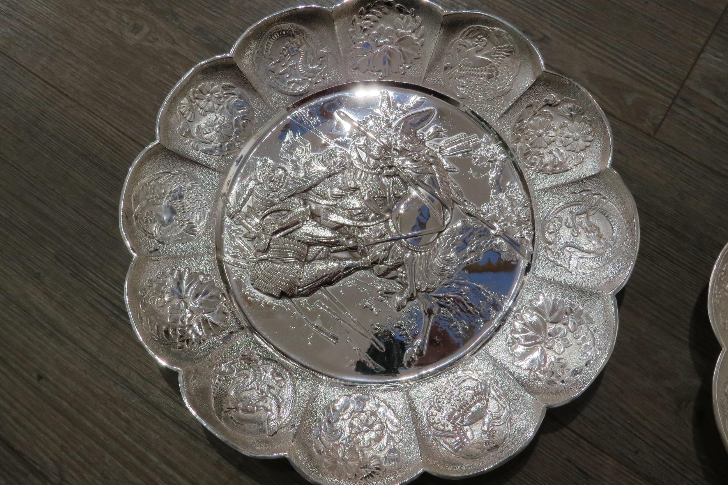 A pair of white metal scalloped form chargers with centres depicting Japanese warriors, 31cm - Image 2 of 3