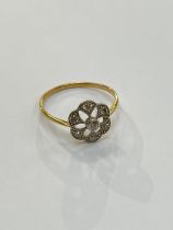 An unmarked gold platinum set diamond daisy ring with open pierced mount. Size S, 2.2g