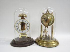 A brass Haller anniversary clock and brass Hermle Skeleton clock, under plastic and glass domes.