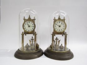 A near identical pair of brass anniversary clocks under glass and plastic domes. Both with white