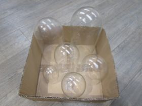 A group of six varying size glass and plastic domes