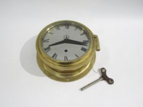 A brass bulkhead clock with Roman numerals and subsidiary seconds dial, made in Germany, with key.