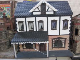 A wooden front opening Tudor style dolls house together with a box of dolls house furniture