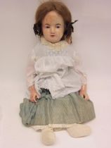A large 19th Century poured wax over papier mache girl doll with fixed striated blue glass eyes