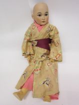 A bisque head character doll in the form of a Japanese lady, with striated brown glass sleepy