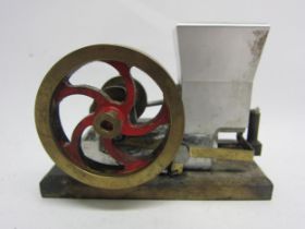 A small hot air stationary engine with single cylinder and polished brass flywheel on wooden base,