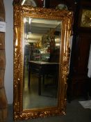 A large rectangular bevel edged mirror in gilded swept frame. 88 x 175 cm.