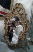 An ornate gilt framed mirror, 70cm x 40cm