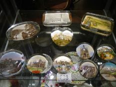 A small collection of souvenir paperweights with various scenes, eleven in total.