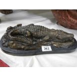 A bronze sleeping crocodile on marble base.