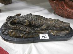 A bronze sleeping crocodile on marble base.