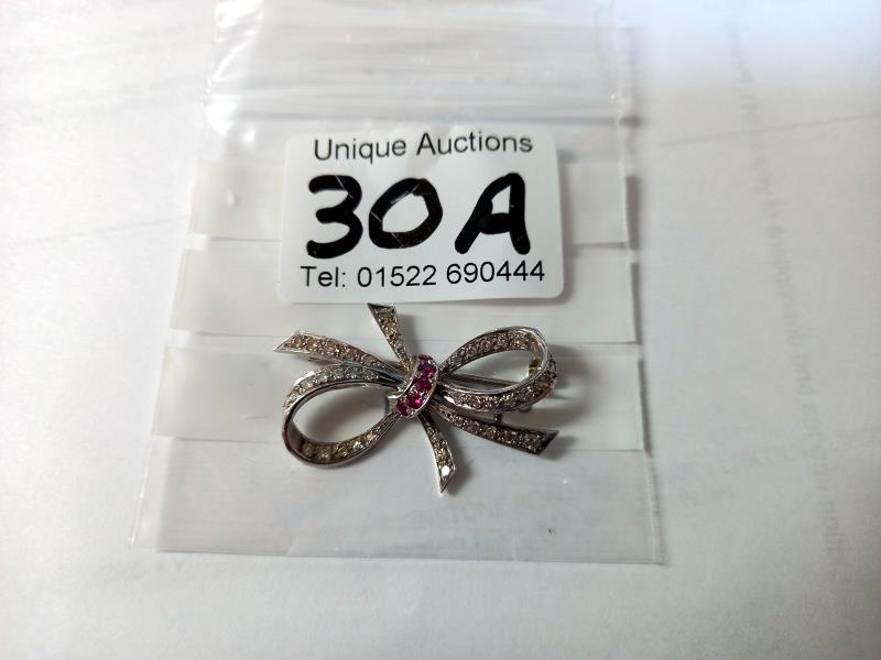 An 18ct white gold & ruby diamond bow brooch. 5.3gms