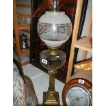 A Victorian oil lamp with brass column, glass font and later shade.