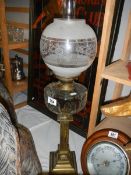 A Victorian oil lamp with brass column, glass font and later shade.