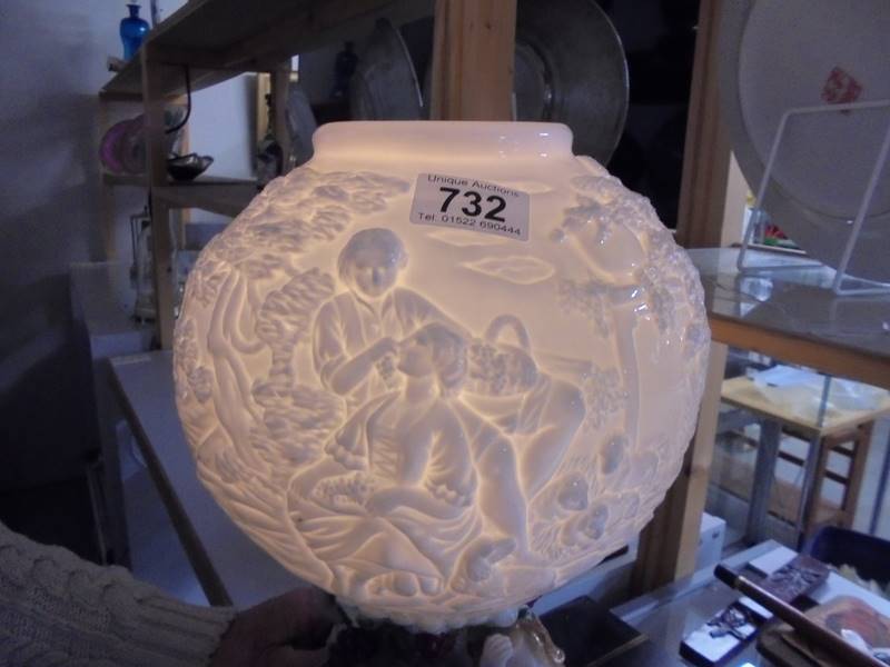 A 20th century porcelain table lamp featuring cherubs with a milk glass embossed shade. - Image 3 of 4