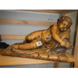A terracotta cherub lying on a bed of roses signed La Route?