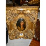 A gilt framed oval portrait of a lady.