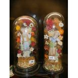 A pair of 19th century bisque porcelain figures under unrelated glass domes.