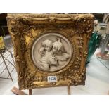 A heavy gilt framed resin plaque of childres in the classical style. Diameter 16cm. frame 29cm x