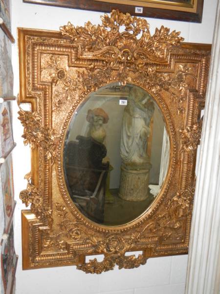 An oval mirror in ornate gilt frame. COLLECT ONLY.