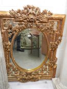 An oval mirror in an ornate gilt frame. COLLECT ONLY.