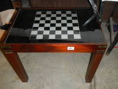 A chess table with glass top and storage compartment with contents.