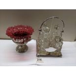 A four bottle cruet and a cranberry glass sugar bowl on plated base, (glass a/f).