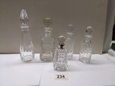 Five crystal/glass bottles with stoppers including one with silver band.