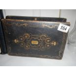 A Victorian box with decorative tooling, brass escutcheon and silk lining.