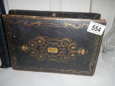 A Victorian box with decorative tooling, brass escutcheon and silk lining.