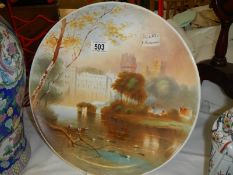 A hand painted plate featuring Warwick castles signed Micklewright, 14" diameter.