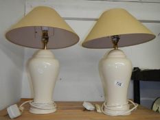 A pair of cream pottery table lamps with shades, height 62 cm.