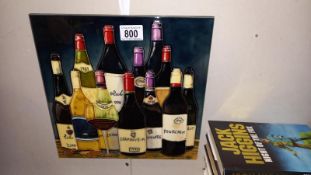 A large hand painted tile/plaque with back stand and hook featuring bottles of wine