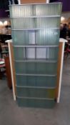 A retro style stacking shelving unit with light blue opaque sliding plastic doors, 76cm x 20cm x