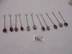 Eleven cocktail forks with semi precious stone tops.