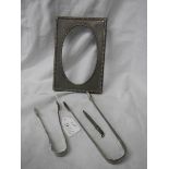 A silver photo frame, two silver sugar tongs and a silver pencil.