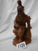 A carved wood figure of an oriental gentleman with bone teeth,