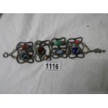An antique metal bracelet featuring fish inset with various gem stones.
