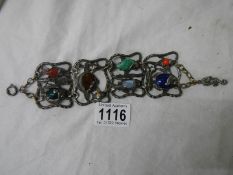 An antique metal bracelet featuring fish inset with various gem stones.