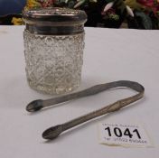 A glass hair pot with silver top and a pair of hall marked silver sugar tongs.