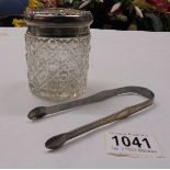 A glass hair pot with silver top and a pair of hall marked silver sugar tongs.