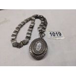 A Victorian silver locket on a decorative un-marked chain.