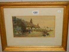 A gilt framed and glazed watercolour featuring a thatched cottage, signed F Meginn.