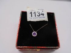 A diamond set pendant with an amethyst centre stone in 9ct gold on a 9ct gold chain.