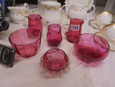 Three cranberry glass jugs and three cranberry glass bowls.