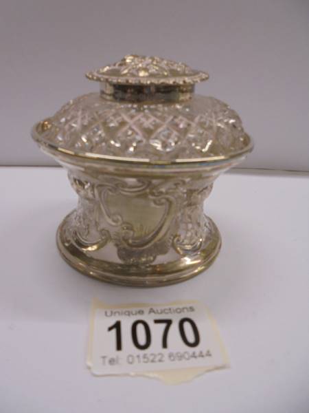 A good glass inkwell resting in a silver stand and with a silver top, (stand 71 grams)