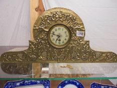 An arts & crafts hammered brass 8 day mantel clock decorated with leaves & grapes, in working order.