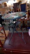A wrought iron folding garden table with 3D coloured glass poppy top, Diameter 35.5cm x height 49.