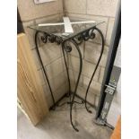 A tall glass topped wrought iron lamp/plant stand height 110cm, slight chip to edge of glass (