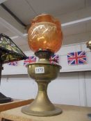 A brass oil lamp with amber glass shade.